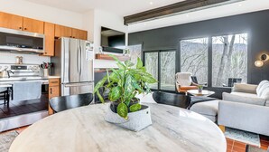 Uma cozinha moderna com eletrodomésticos de aço inoxidável, uma mesa de jantar de mármore e uma grande janela com vista para uma paisagem nevada.