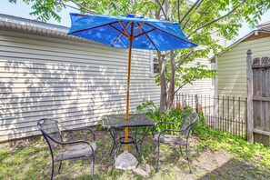 A patio with a table and chairs, a blue umbrella, and a wooden fence. - 1/2 Mi to Pier: Wfh-friendly Apt in Maine! (Old Orchard Beach)