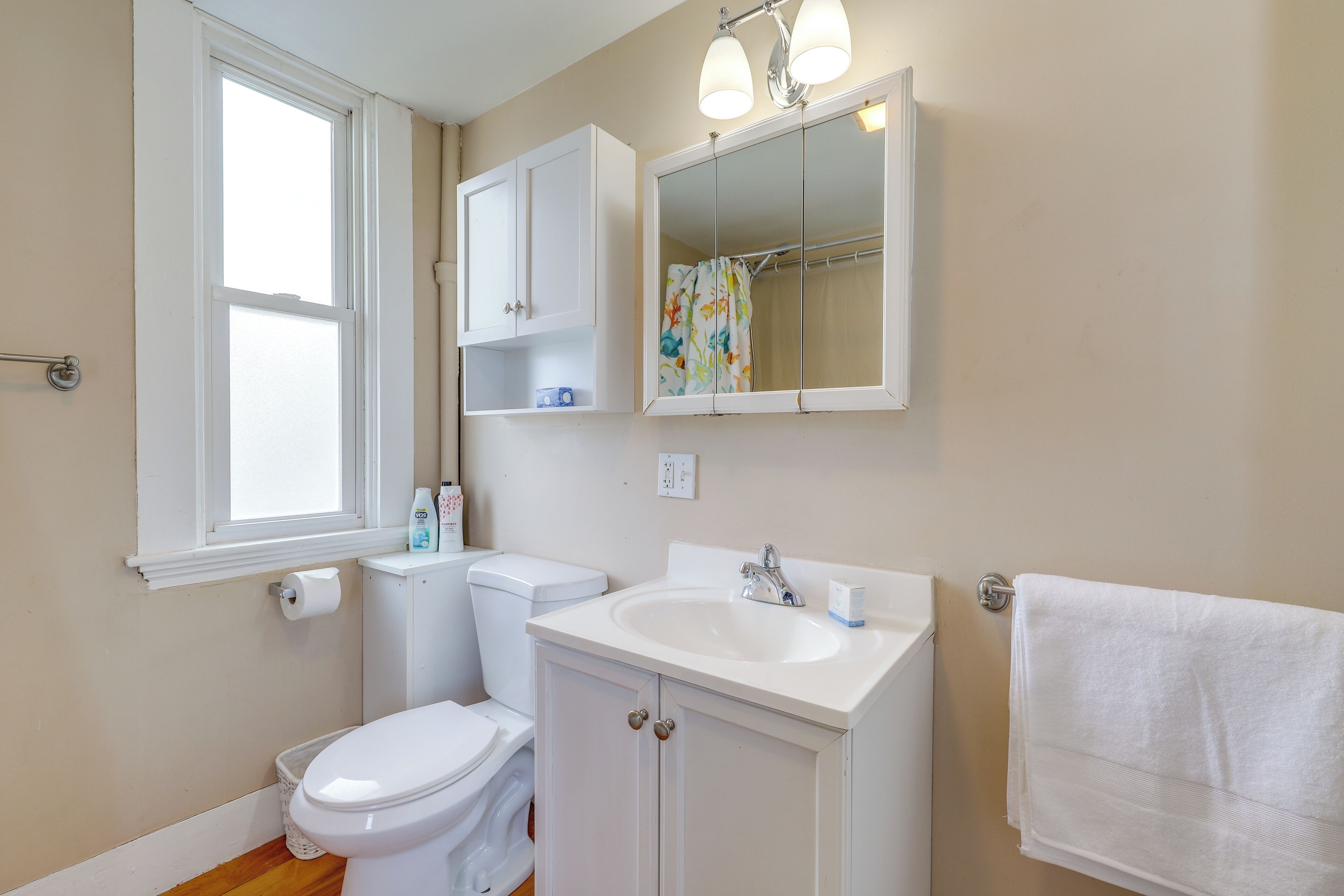 Une salle de bain équipée de toilettes, d’un lavabo, d’un miroir et d’un porte-serviettes.