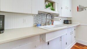 A modern kitchen with white cabinetry, a white countertop, a stainless steel coffee maker, a sink, and a backsplash. - 1/2 Mi to Ocean: Cozy Apt in Old Orchard Beach (Old Orchard Beach)