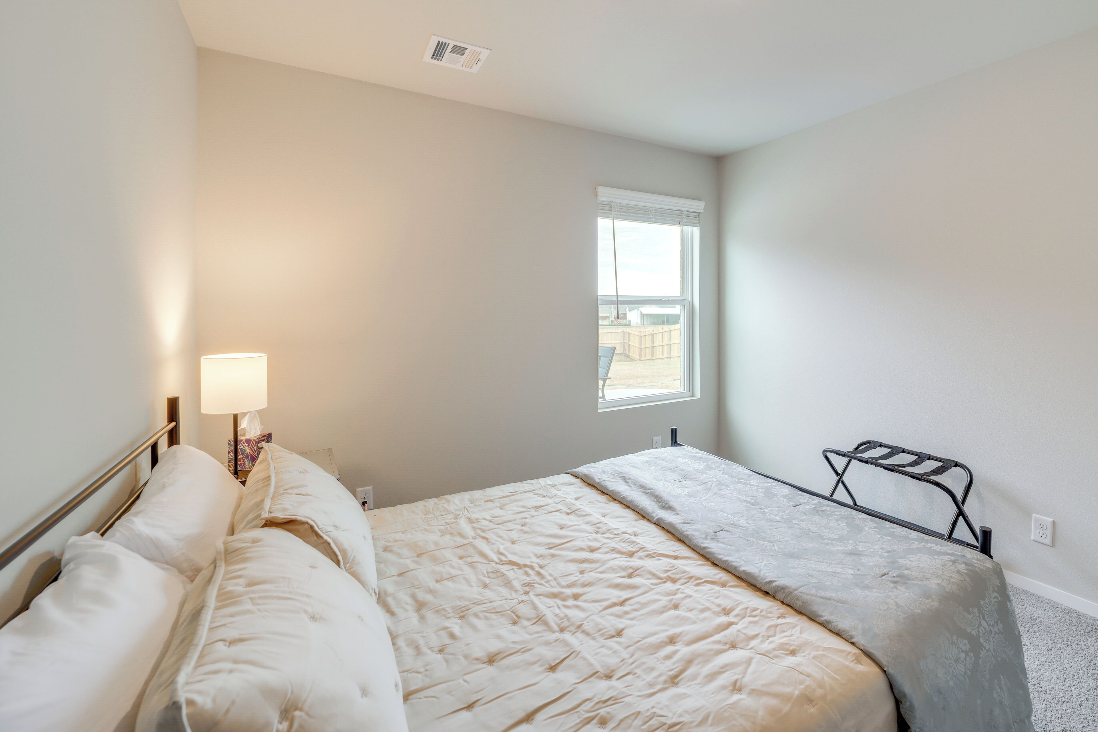 A bedroom with a bed, a bedside lamp, a window, and a radiator.