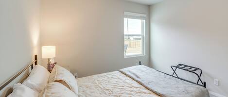 A bedroom with a bed, a bedside lamp, a window, and a radiator.