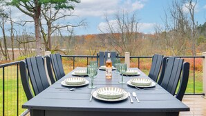 A table set for six with plates, glasses, and cutlery, overlooking a natural landscape. - Walk to Lake: Pet-friendly Cottage in Jamestown! (Pymatuning South)
