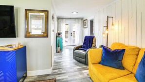 A living room with a yellow sofa, a blue armchair, and a blue cabinet. There is a door leading to a balcony. - Walk to Casino: Home w/ Deck in Hot Springs! (Hot Springs)