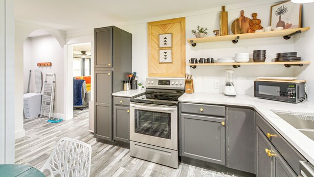 A modern kitchen with stainless steel appliances, wooden cabinetry, and built-in shelves. - Walk to Casino: Home w/ Deck in Hot Springs! (Hot Springs)