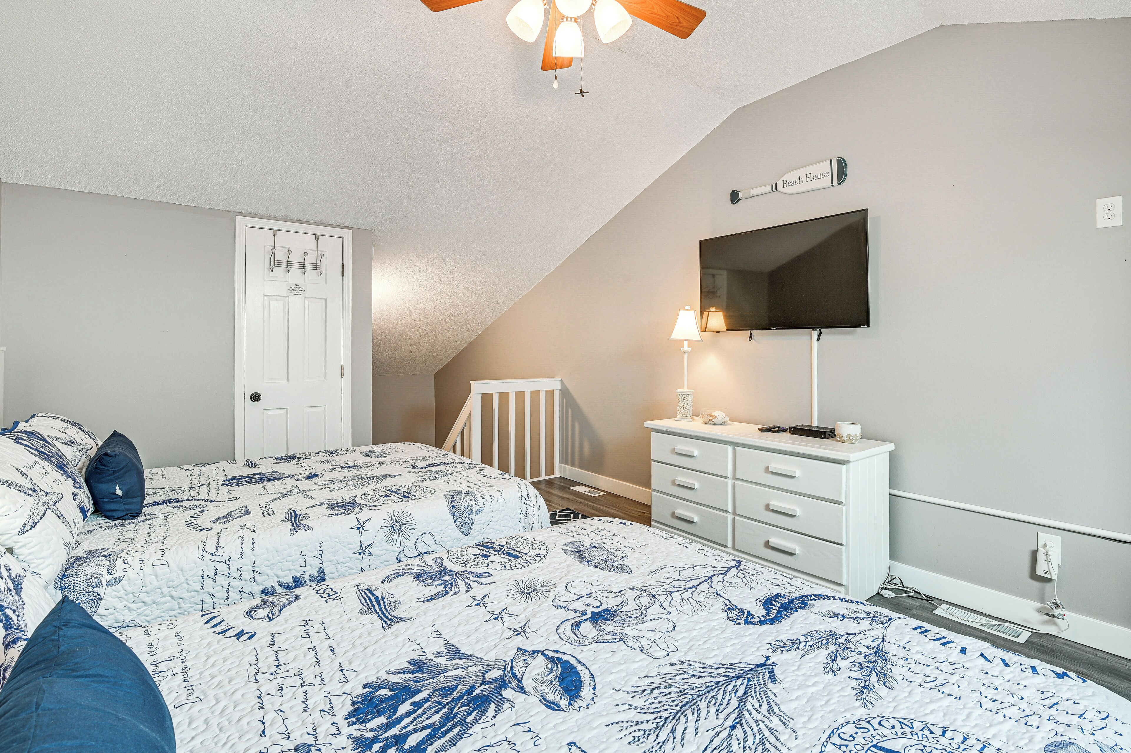 Een slaapkamer met een bed, een dressoir, een televisie en een plafondventilator.