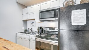 A modern kitchen with white cabinets, a stainless steel refrigerator, a microwave, a stove, and a sink. - Walk to Beach: Condo w/ Balcony in Murrells Inlet! (Murrells Inlet)