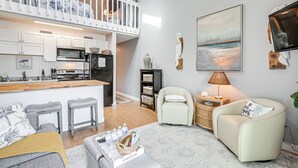 A modern kitchen with white cabinetry, a central island, and a dining area with stools. - Walk to Beach: Condo w/ Balcony in Murrells Inlet! (Murrells Inlet)