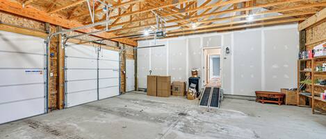 Un garage spacieux avec des poutres en bois apparentes, un sol en béton et une porte de garage blanche.