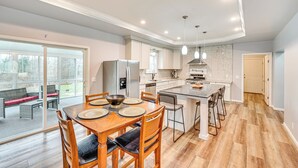 A modern kitchen with a dining area, large windows, and a view of the outdoors.
