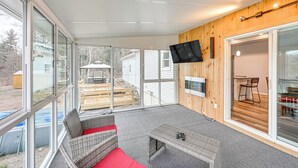 A covered patio with wicker furniture, a flat-screen TV, and large windows offering a view of the backyard.