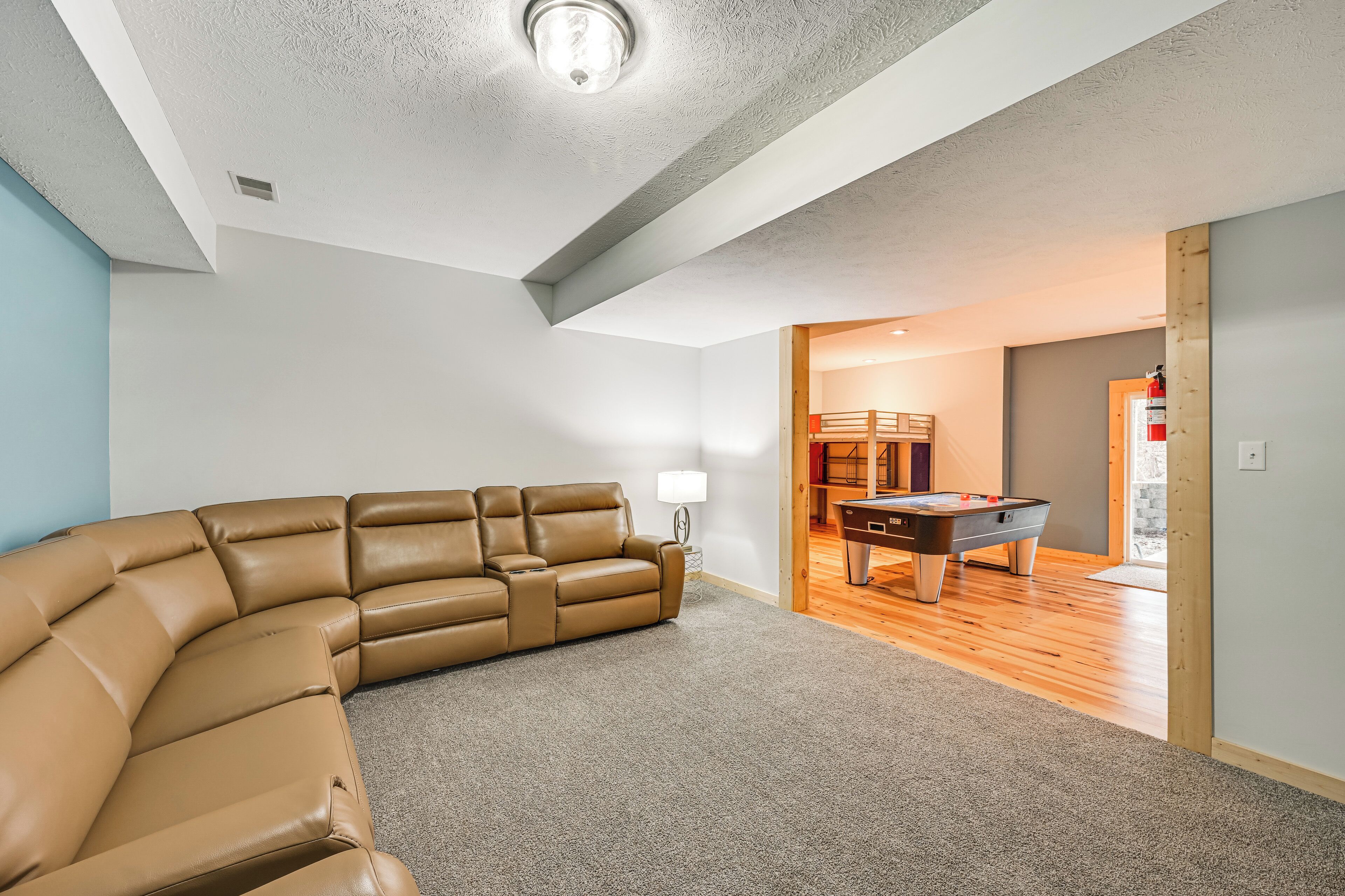 A modern living room with a large L-shaped leather sofa, a pool table, and a lamp.