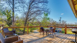 Une terrasse en bois, meublée de mobilier en osier, avec un barbecue et une vue sur le paysage environnant.