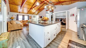 Un loft spacieux avec un plafond haut, un îlot central doté d’un évier, un coin cuisine et un espace de vie avec un canapé.