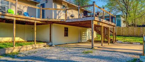 A two-story house with a covered patio, a wooden deck, and a fenced yard.