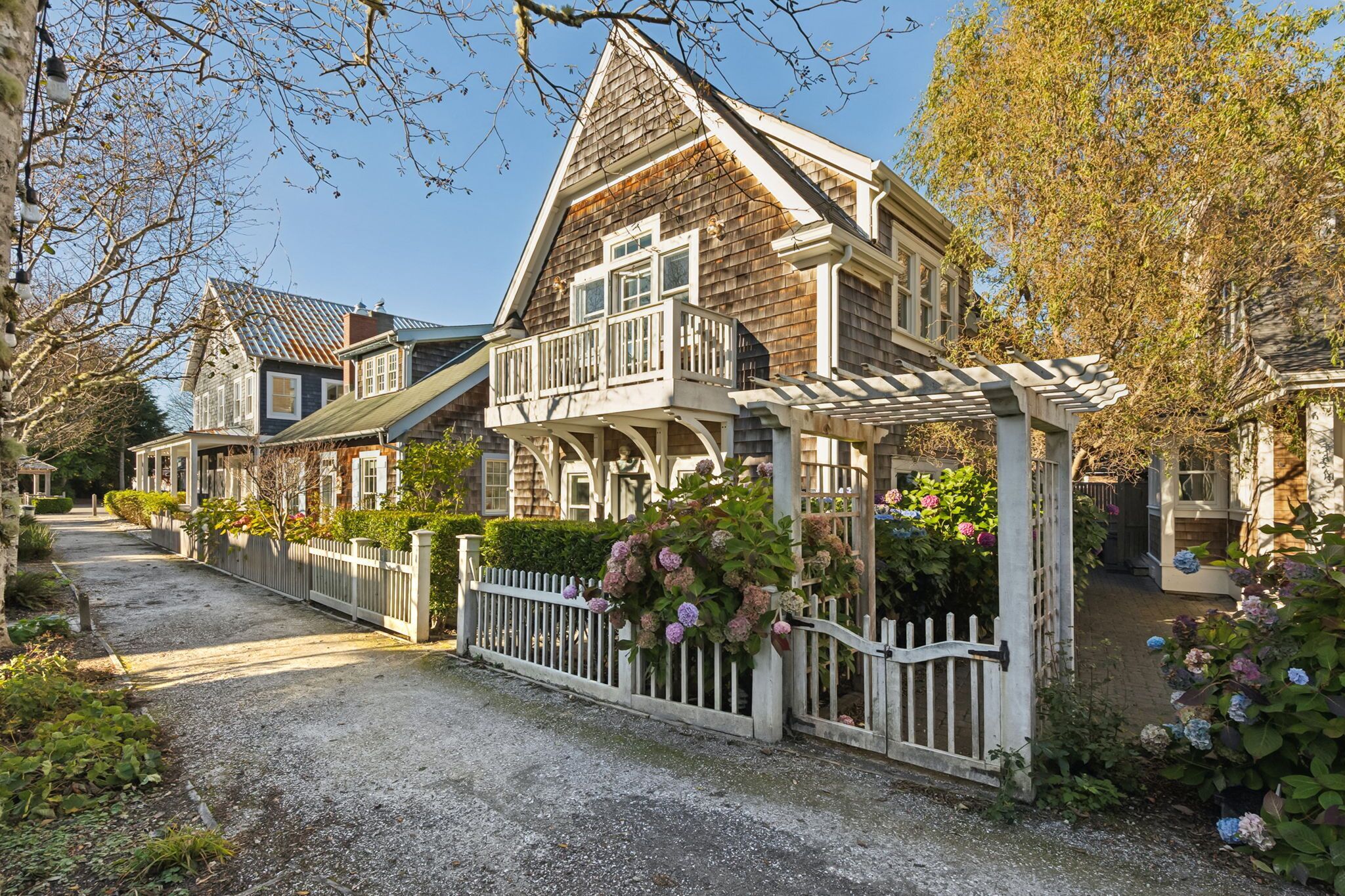A traditional wooden house with a white porch and a gravel driveway.
