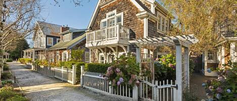 A traditional wooden house with a white porch and a gravel driveway.