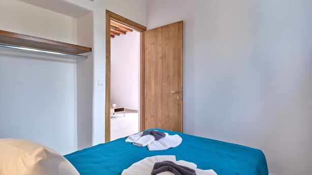 Une chambre d’hôtel avec un lit, une porte en bois et une petite table sur laquelle se trouve une tasse.