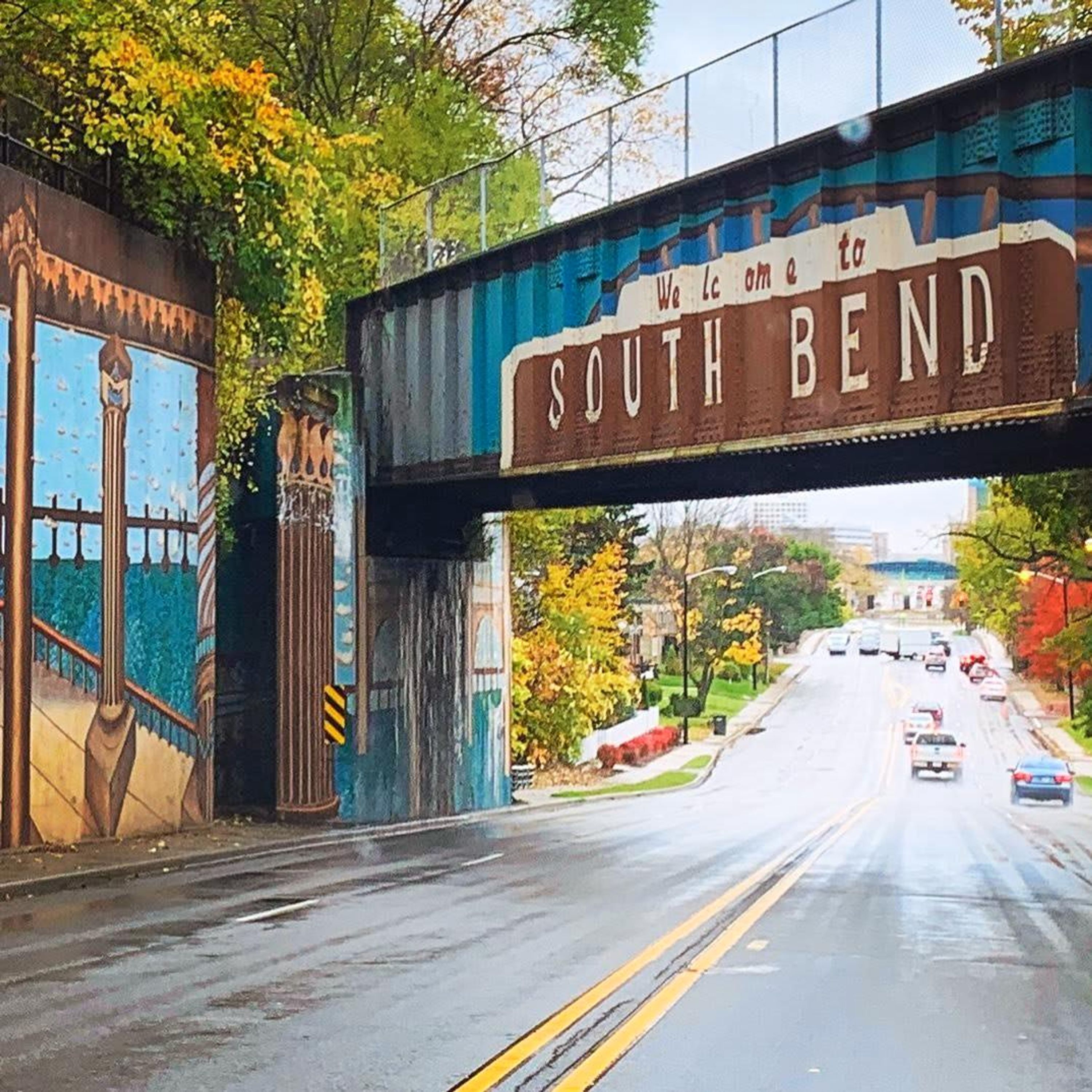 A street under a bridge with a sign reading "We are on to SOUTH BEND".