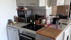 A compact kitchen with a dishwasher, oven, microwave, and a washing machine. - Maison Front de Mer Aresquiers | Direct beach access | 4 bedrooms (Frontignan)