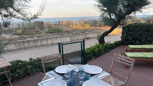 A round table set for four with plates, cutlery, and glasses, overlooking a beach. - Maison Front de Mer Aresquiers | Direct beach access | 4 bedrooms (Frontignan)
