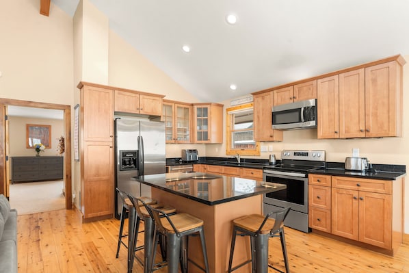 A modern kitchen with wooden cabinets, stainless steel appliances, and a central island with bar stools.