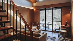 A modern living room with a wooden staircase, large windows, and a cozy seating area. -  The Himalayan Tyangboche (Lukla)
