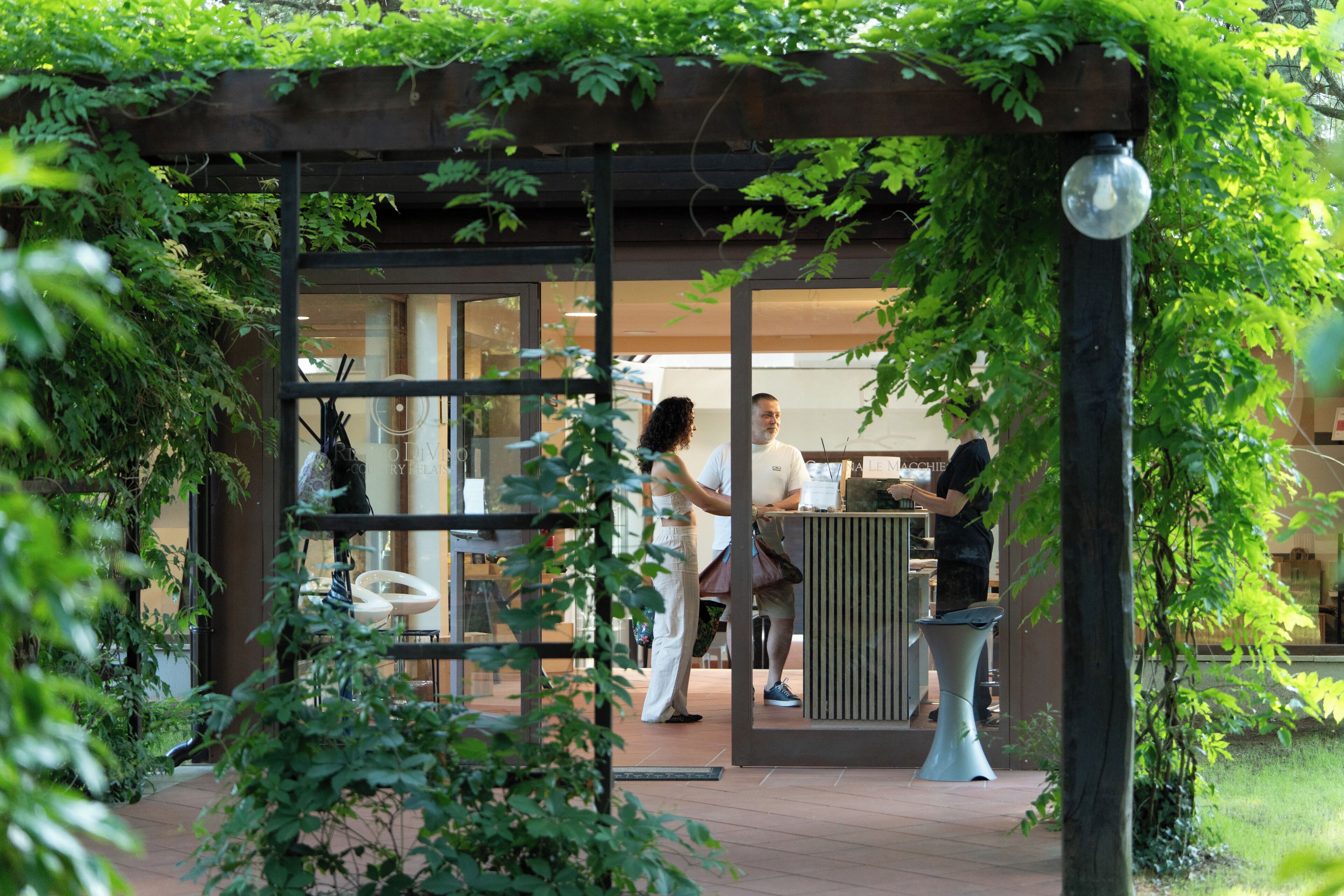 Un área de estar al aire libre con una pérgola, cerramiento de cristal y una mesa de metal.