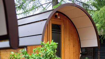 A wooden structure with a curved roof, a door, and a small set of stairs leading up to it.
