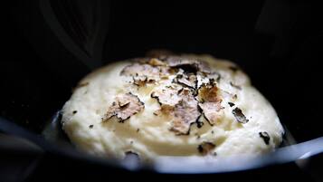 A close-up of a creamy dessert with a caramelized top, possibly a crème brûlée, in a dark bowl.