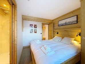 A room with a wooden bed, white linens, and a framed picture on the wall.