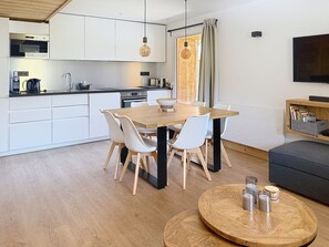 A modern kitchen with white cabinets, a wooden dining table, and a round coffee table. - Le Chaberton | Across from ESF & the slopes – 6–8 people – Montgenèvre (Unknown)