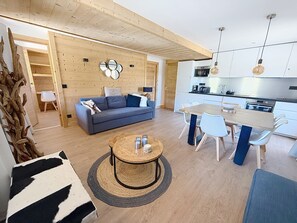 A modern living space with a sofa, dining table, and kitchen area.