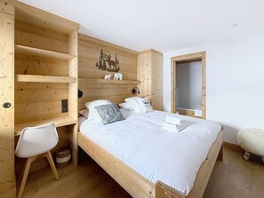 A wooden room with a bed, a chair, and a shelf with decorative items. - Le Chaberton | Across from ESF & the slopes – 6–8 people – Montgenèvre (Unknown)