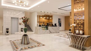 Eine moderne Hotelhalle mit Empfangstresen, Marmorböden und zeitgemäßen Leuchten.