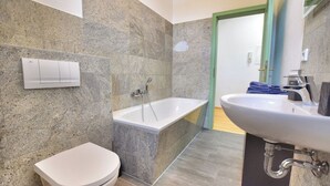 A modern bathroom with a bathtub, toilet, and sink. - Vacation apartment "Schwalbennest (Naumburg (Saale))