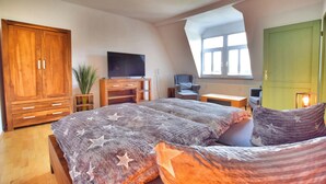 A bedroom with a large bed, a TV, a desk, and a wardrobe. - Vacation apartment "Schwalbennest (Naumburg (Saale))