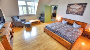 A bedroom with a large bed, two chairs, a desk, and a view of the outside through a window. - Vacation apartment "Schwalbennest (Naumburg (Saale))