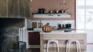 Una cocina de diseño rústico con una isla de madera, taburetes blancos de barra y una chimenea de piedra.