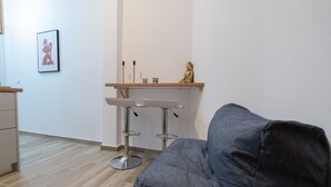 Ein modernes Wohnzimmer mit grauem Sofa, einem Holztisch und einer kleinen Bar mit Hockern.