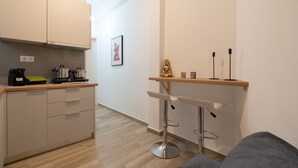 Eine moderne Küche mit Arbeitsplatte, Herd und Schränken. Auf einem Regal steht eine kleine Buddha-Statue.