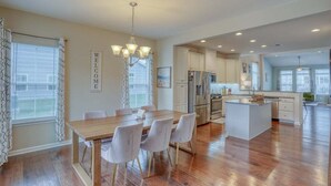 A spacious kitchen with a central island, white cabinetry, and a dining area with a chandelier. - Coastal Club Villa: Resort Amenities 3 BR, 2.5 BA (Lewes)