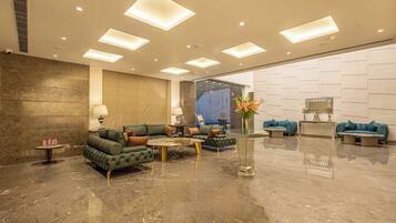 A spacious lobby with a green sofa set, a coffee table, and a reception desk.
