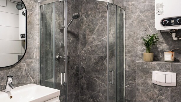 Une salle de bain moderne avec une douche à parois de verre, un lavabo blanc et des toilettes.