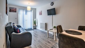 A modern living room with a sofa, a dining table, and a TV. - Aldridge Square (Birmingham)