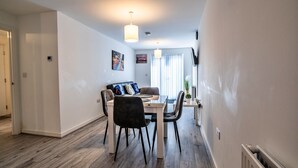 A modern dining area with a white table, black chairs, and pendant lighting. - Aldridge Square (Birmingham)