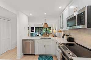 A modern kitchen with white cabinetry, stainless steel appliances, and a central island.