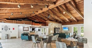 A spacious living area with a high wooden ceiling, a stone wall, and a large TV screen. - C-122 - Luxury Condo - Easy Walk to Amenities! (Naples)