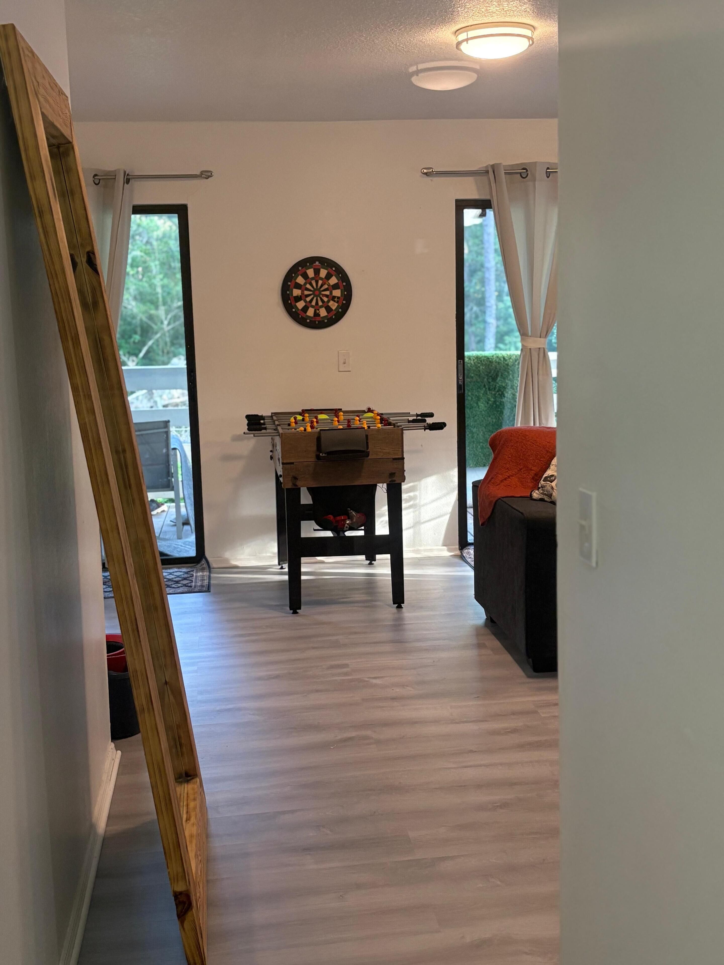 Ein Zimmer mit Kicker, Dartscheibe und einer Couch.