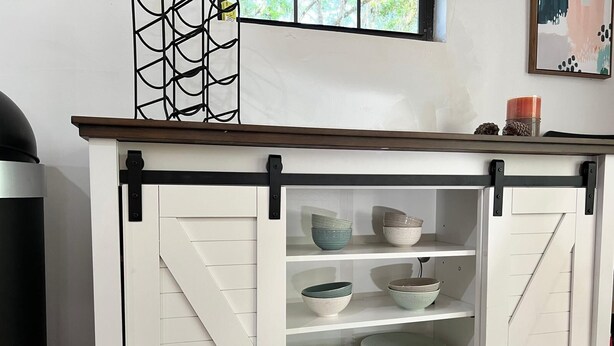 A white cabinet with black handles and shelves, containing bowls and plates. - Blue Sky StiltsHouse in a Secluded Forest. (Ocala)